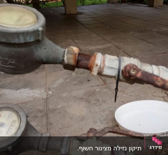 מד מים חלוד עם צינור וברז על רצפה